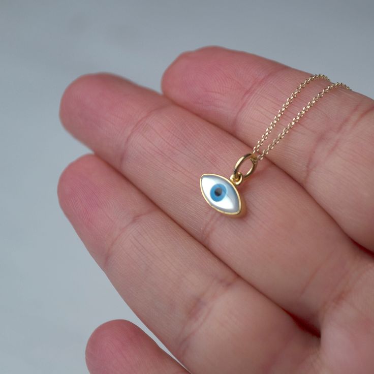 Εxtra tiny 14k solid gold evil eye pendant.  The pendant measures 11mm / 0.4 inches The evil eye pendant is available in 14k yellow gold with a white evil eye.  The  eye is made of mother of pearl (mop). The backside is closed, smooth 14k solid gold. Available with a solid 14k gold chain or as pendant only. Chains are available in 3 lengths, 16inches/40cm, 18inches/45cm and 20 inches/50cm Perfect gift for Valentine or any other special occasion. Comes in a gift box. White 14k Gold Round Charm Necklaces, White 14k Gold Round Charm Necklace, 14k Yellow Gold Evil Eye Jewelry, 14k Yellow Gold Jewelry With Evil Eye, Everyday Yellow Gold Evil Eye Charm Necklaces, 14k Gold Charm Necklace With Evil Eye, 14k Gold Round Evil Eye Charm Necklace, 14k Gold Evil Eye Charm Necklace As Gift, Dainty 14k Gold Charm Necklace With Evil Eye