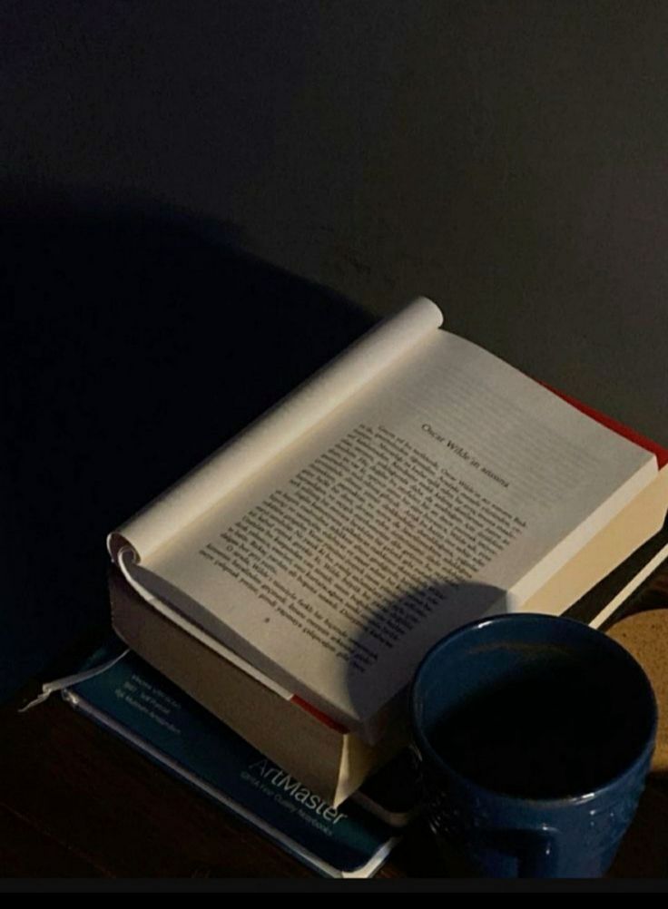 an open book sitting on top of a table next to a cup