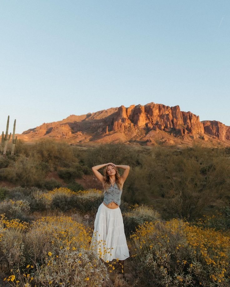 a woman is standing in the desert with her arms behind her head