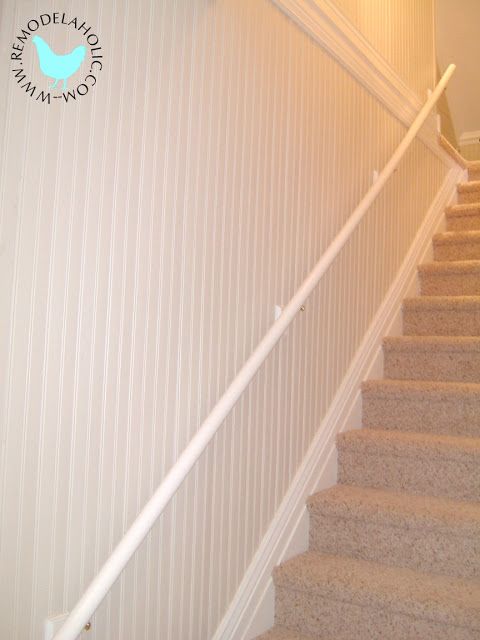 a white stair rail on top of a set of stairs next to a wall and carpeted floor