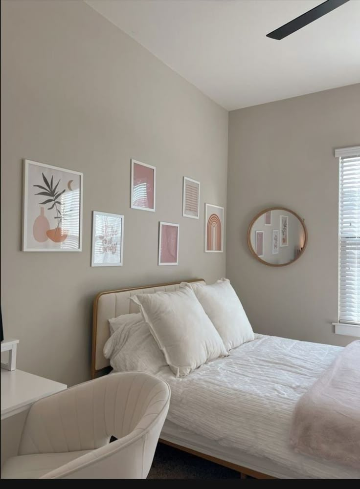 a white bed sitting in a bedroom next to a window with lots of pictures on the wall