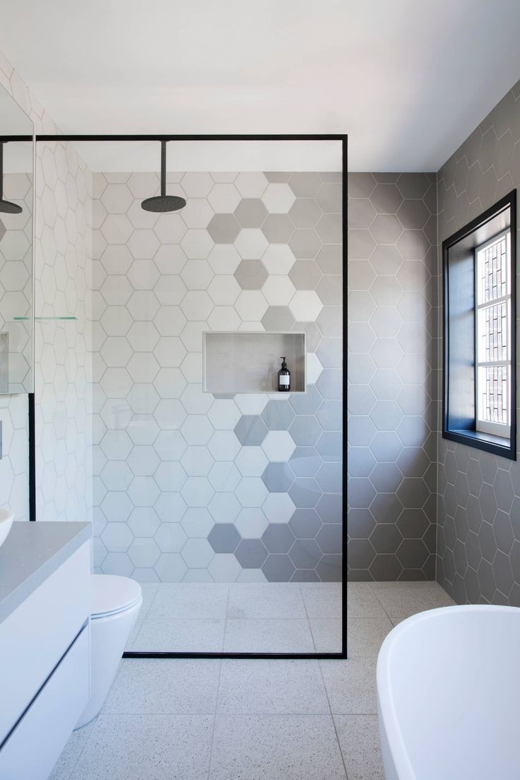 a modern bathroom with hexagonal tiles on the shower wall and bathtub area