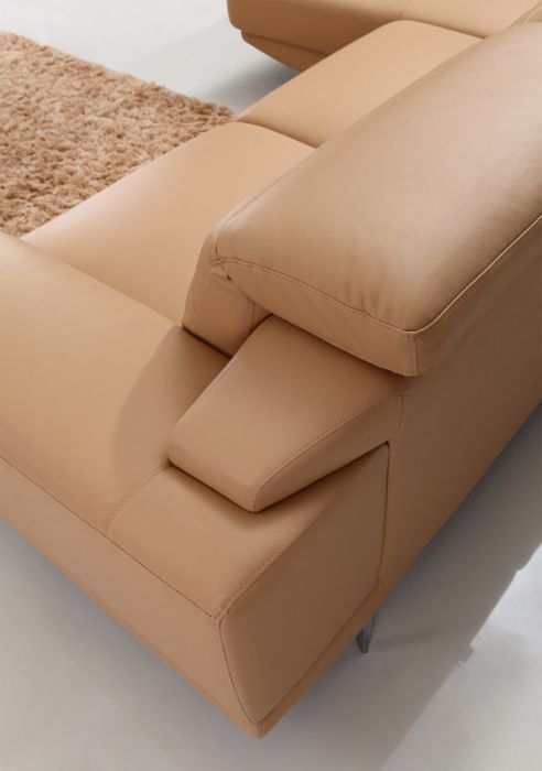 a tan leather couch sitting on top of a white floor next to a brown rug