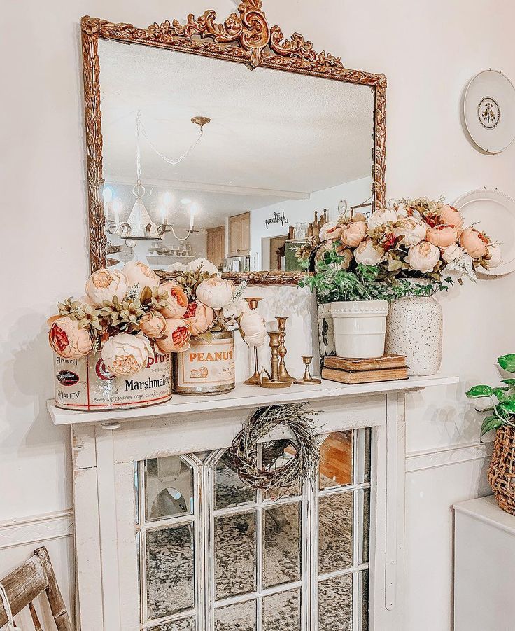 a fireplace mantel with flowers on top and candles in the middle, next to a mirror