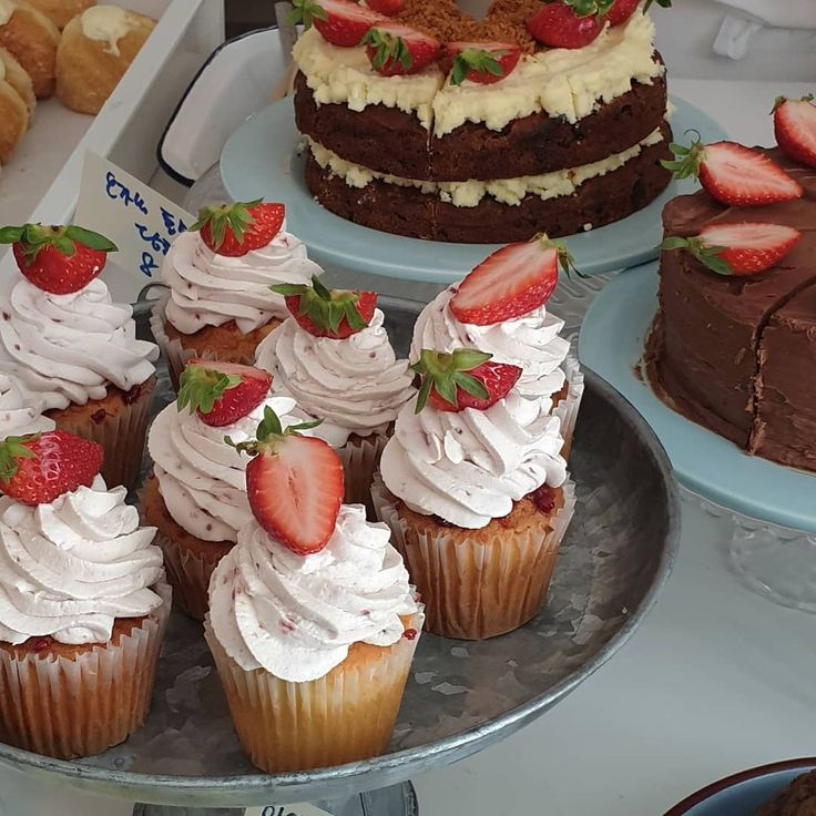 there are many different cakes and cupcakes on the table with strawberries in them