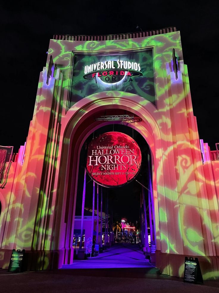 the entrance to universal studios is lit up with colorful lights and an arch that leads into it