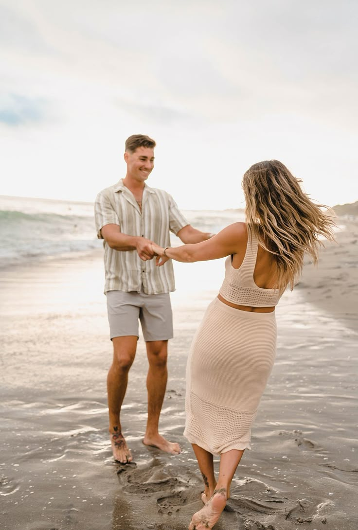 a man and woman holding hands on the beach