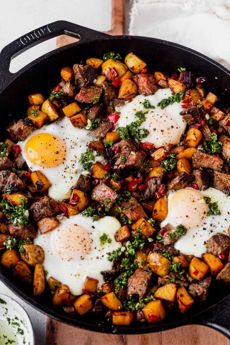 two fried eggs are on top of the hash browns in a cast iron skillet