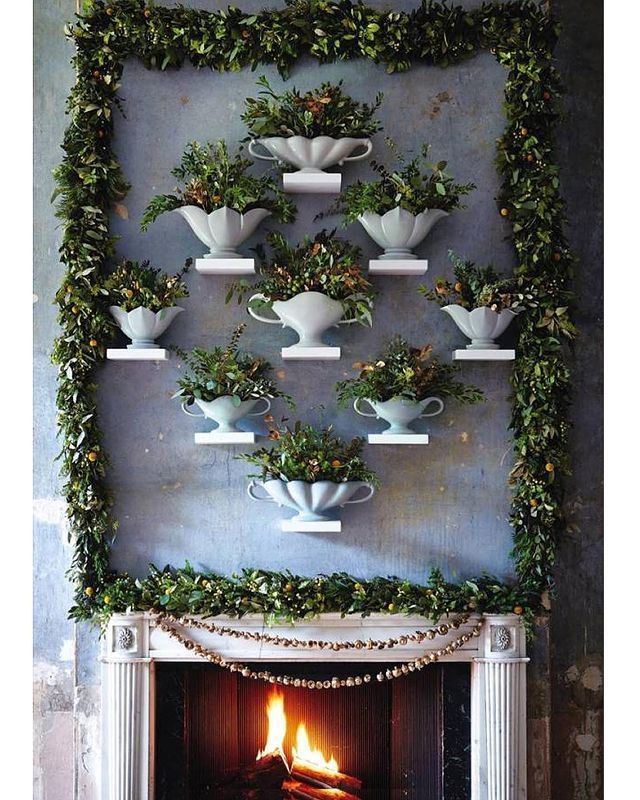 the fireplace is decorated with greenery and tea cups on it's mantel