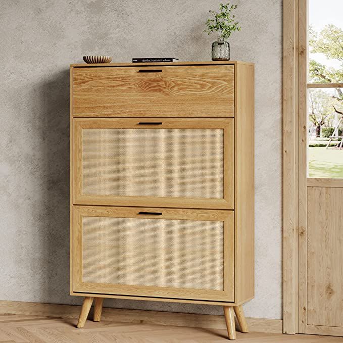 a wooden cabinet with two drawers in front of a window and a potted plant on top of it