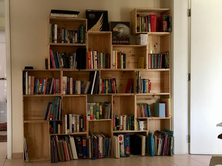 a bookshelf filled with lots of books on top of a white tiled floor