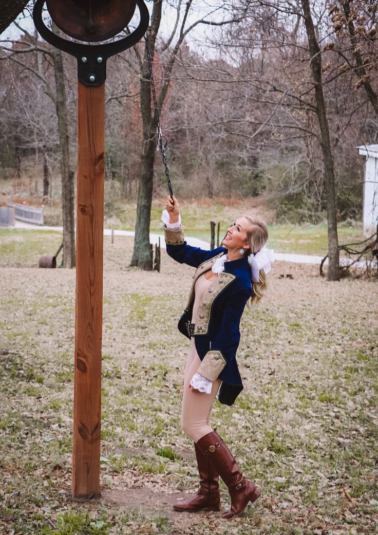 a woman in riding boots is swinging on a rope at the park with her horse