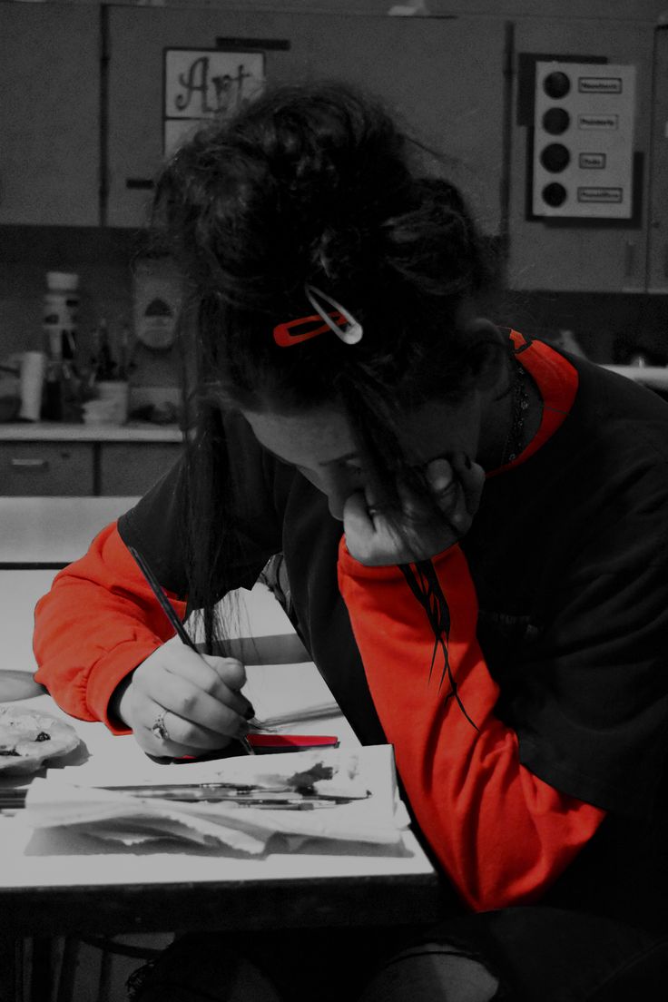 a woman sitting at a table writing on a piece of paper