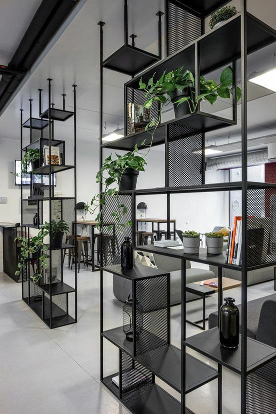 an office with black shelving and plants