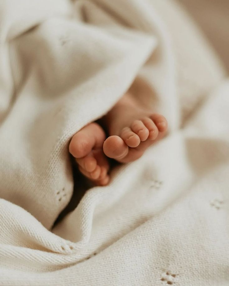 a baby's feet are tucked under a blanket