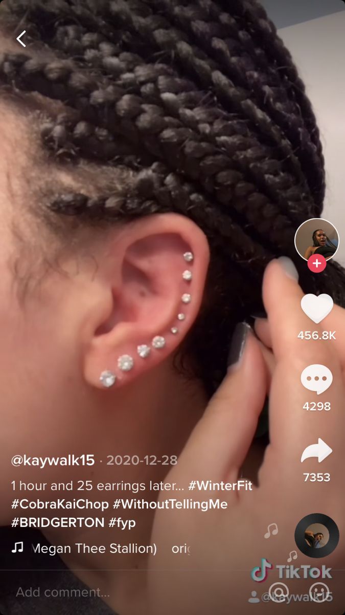 a woman with braids and piercings is looking at her cell phone while she's wearing an earring