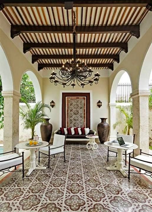 a living room with chairs, tables and a chandelier hanging from the ceiling