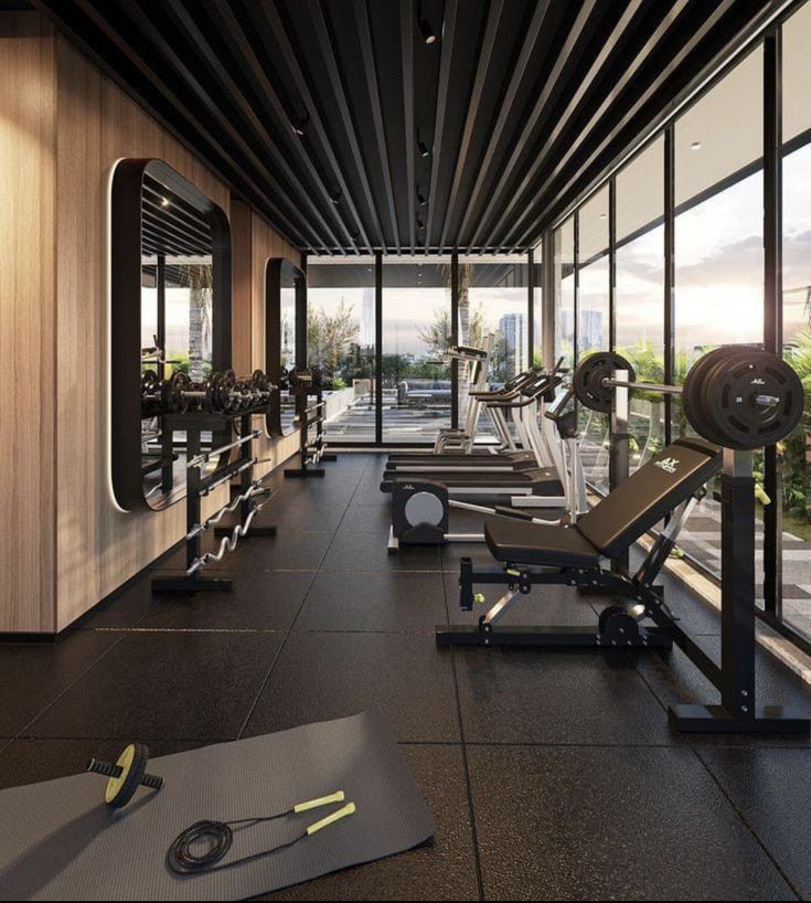 an empty gym with rows of exercise machines and treadmills in front of large windows