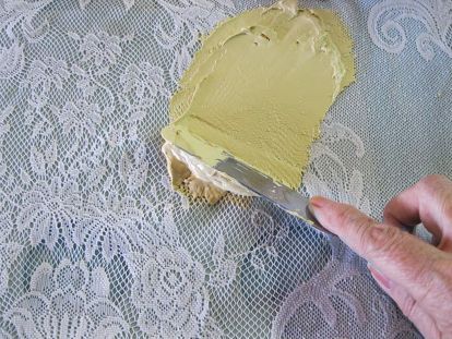 someone is using a knife to paint the lace on a tablecloth with white doily