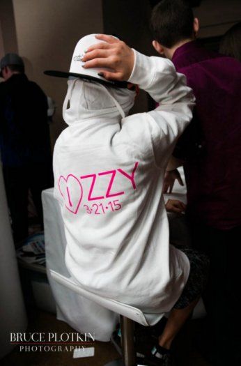 a person wearing a white jacket with pink letters on it and a hat over their head