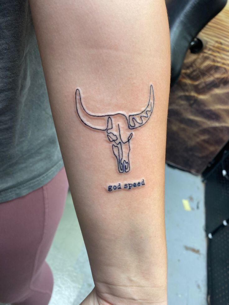 a woman's arm with a tattoo on it that reads god speed and an image of a bull skull