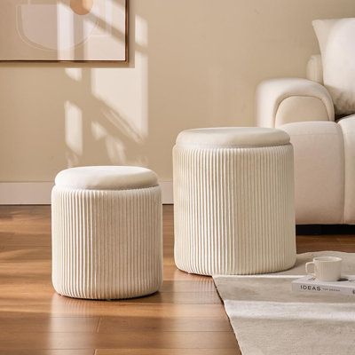 two white stools sitting on top of a hard wood floor next to a couch