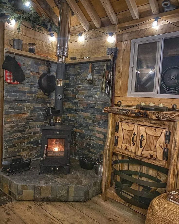 a wood burning stove sitting inside of a living room next to a fire place with lights on