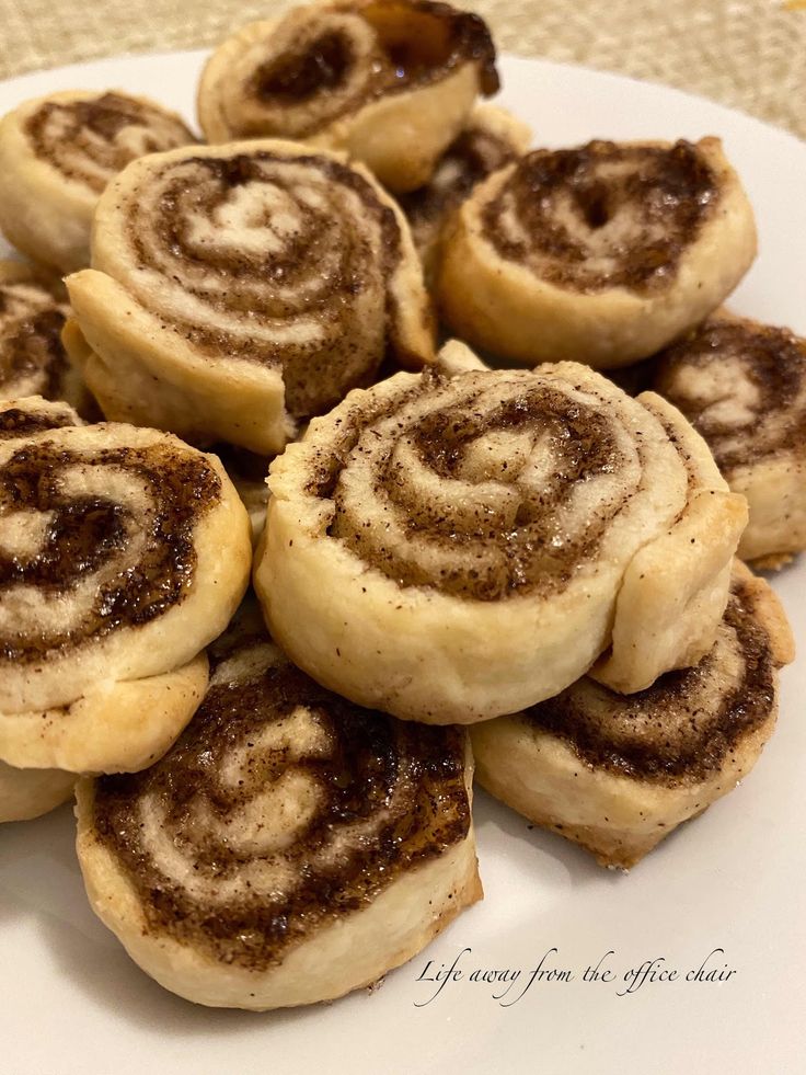 cinnamon rolls on a white plate sitting on a table