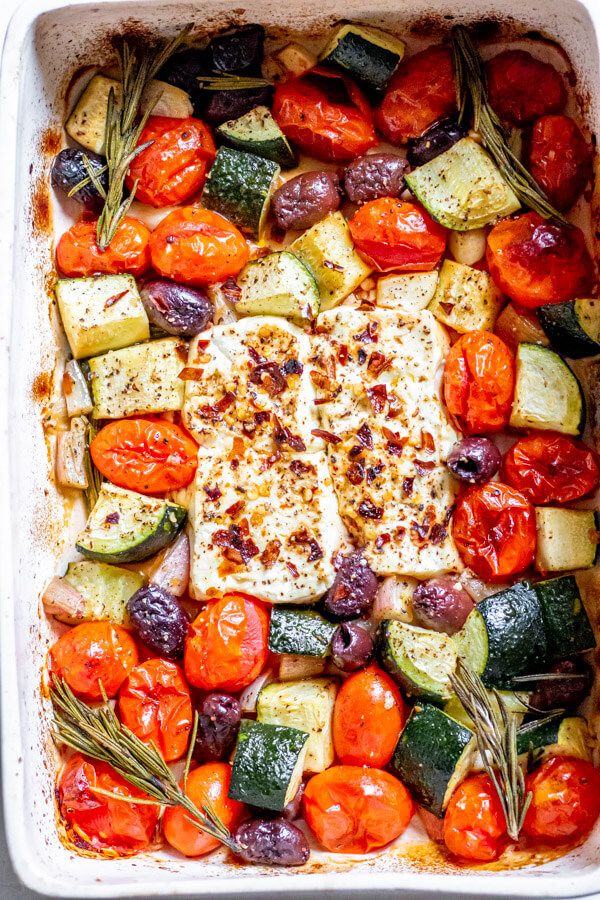 a casserole dish filled with vegetables and topped with cheese, herbs and seasonings