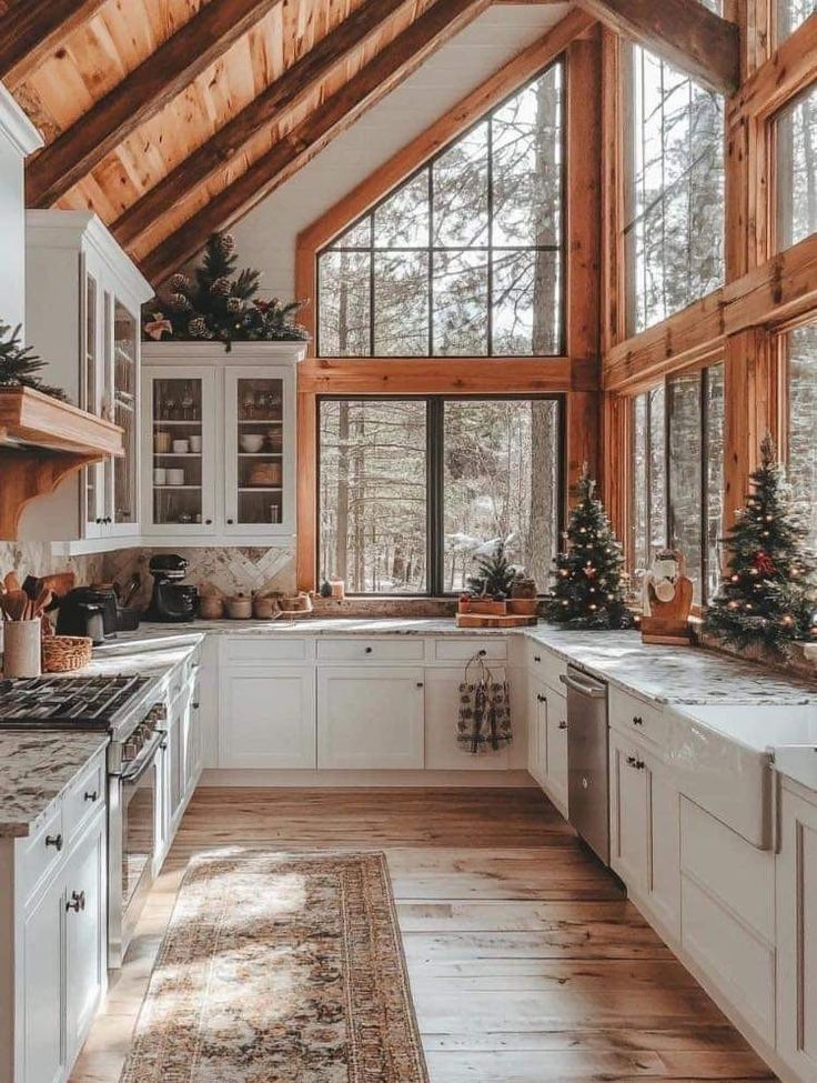 a kitchen with wooden ceilings and white cabinets, christmas trees on the counter top, and an area rug in front of the window