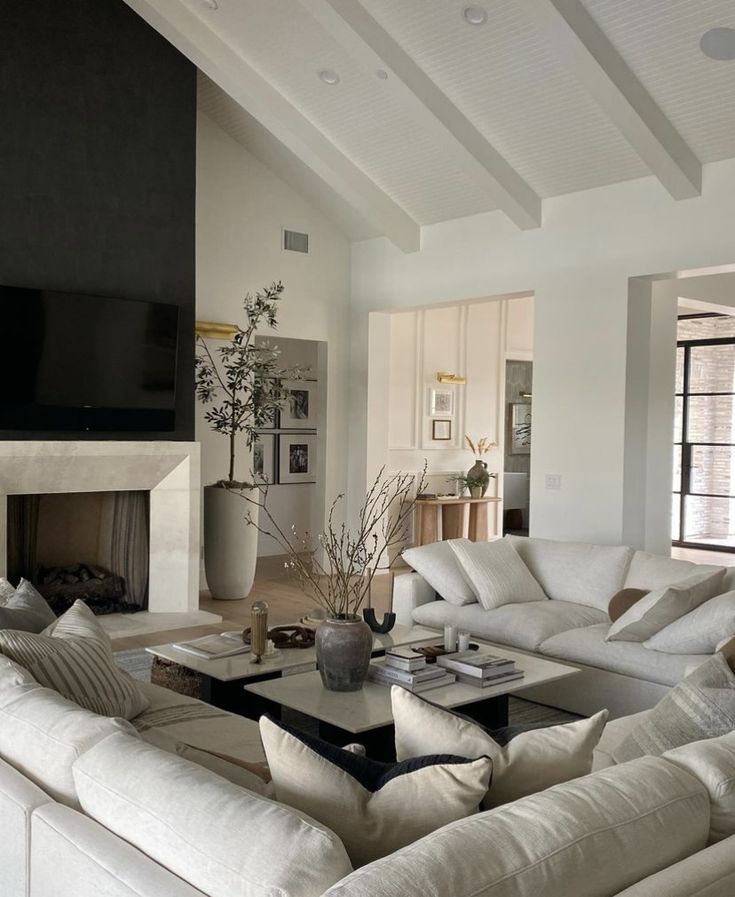 a living room filled with white furniture and a flat screen tv mounted on the wall