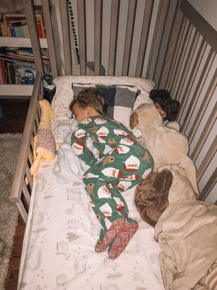 a little boy sleeping in his bed with stuffed animals