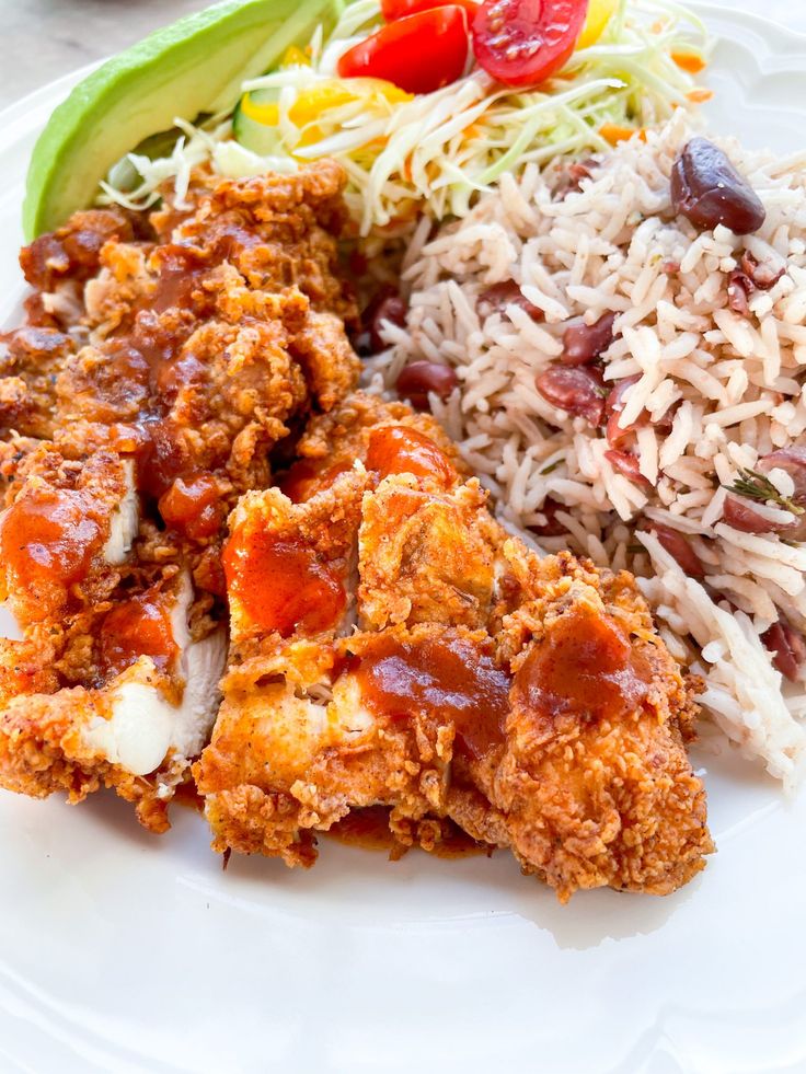 a white plate topped with rice, meat and veggies next to a salad