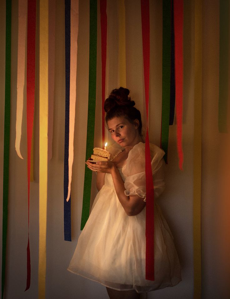 A girl in a fluffy white dress stands amidst birthday streamers holding a cake with a lit candle Birthday Party Shoot Ideas, Birthday Self Portrait, Retro Birthday Photoshoot, Flash Photography Aesthetic Birthday, Film Photography Birthday, Photoshoot Birthday Ideas, Fun Birthday Photoshoot Ideas, Vintage Birthday Photoshoot, Birthday Photoshoot Ideas Confetti