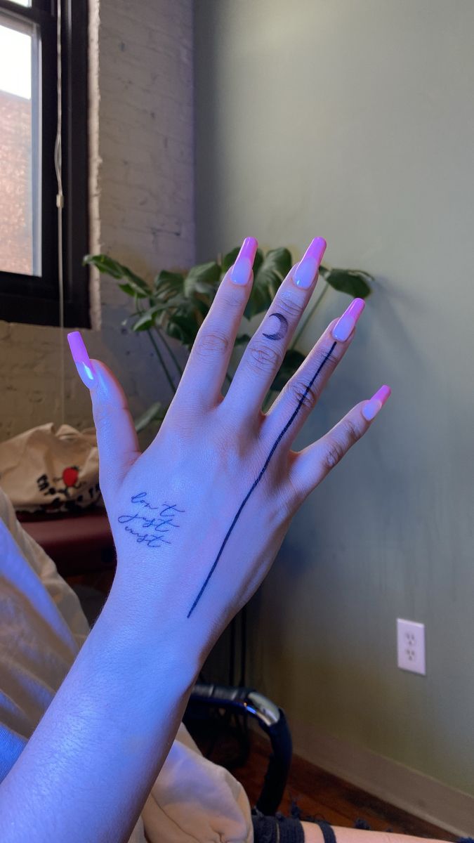 a woman's hand with pink and blue nail polish on her left arm, in front of a window