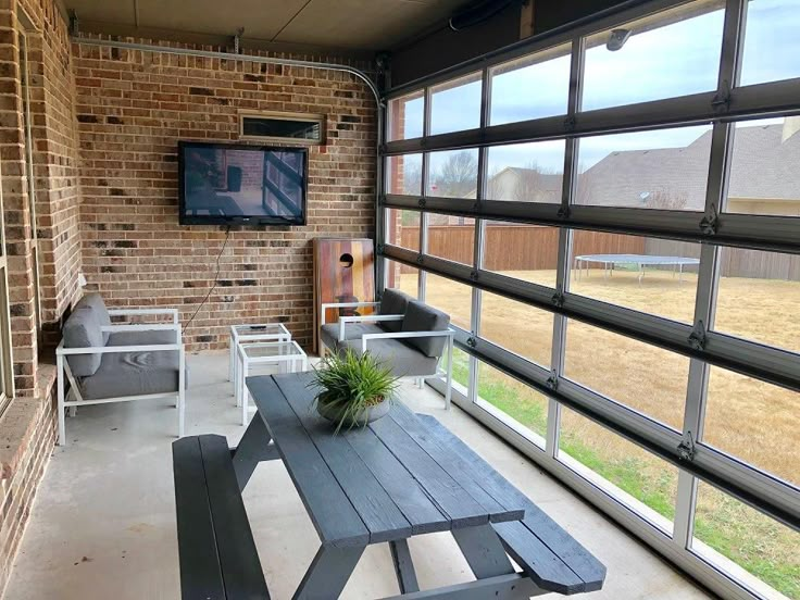 a table and chairs on a porch with a television mounted to the wall above it