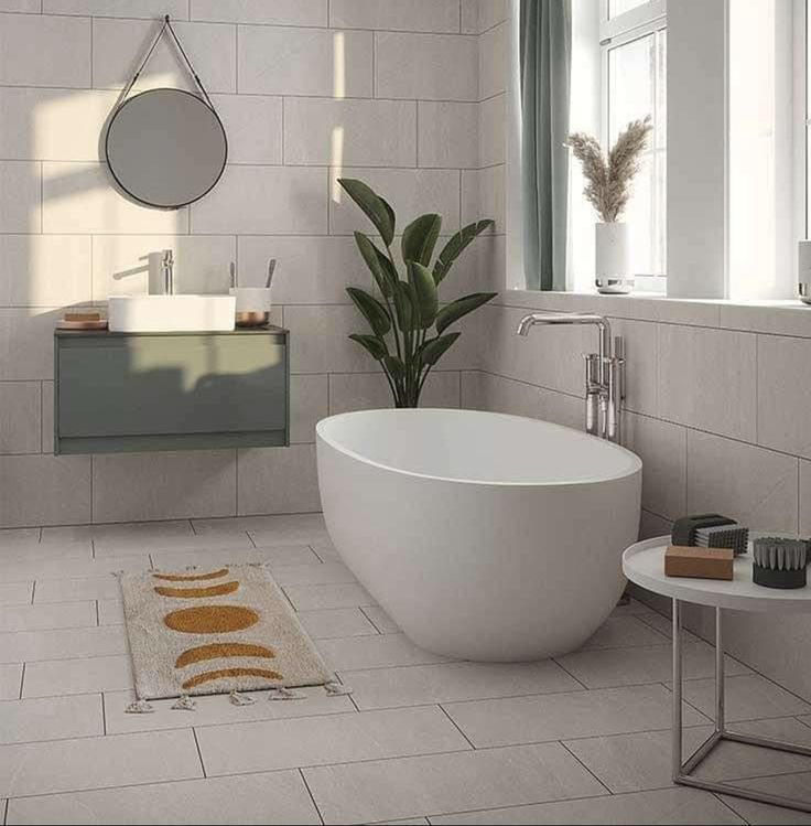 a white bath tub sitting in a bathroom next to a sink and mirror on the wall