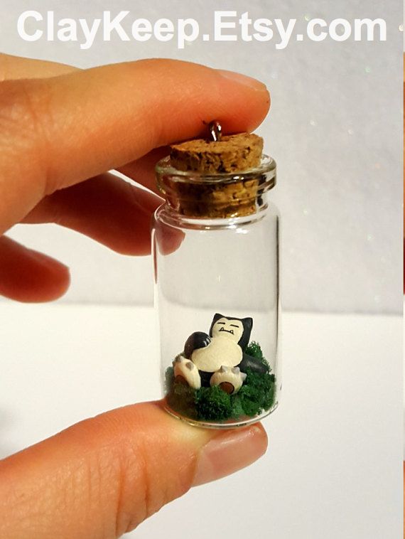 a hand holding a tiny glass bottle filled with grass and a small white dog in it