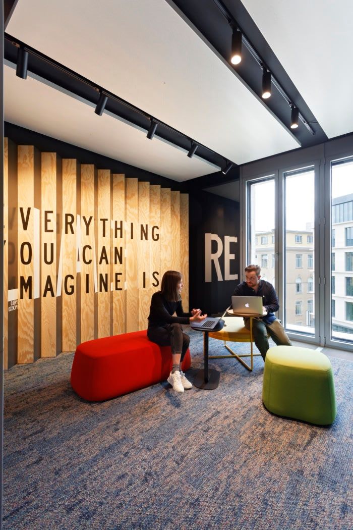 two people are sitting at a table in an office with large windows and wooden panels on the wall