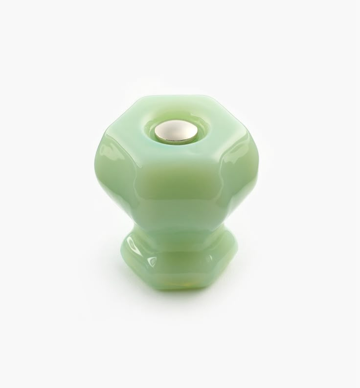 a light green glass knob with a hole in the middle on a white background,