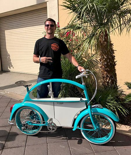 a man standing next to a blue and white bike