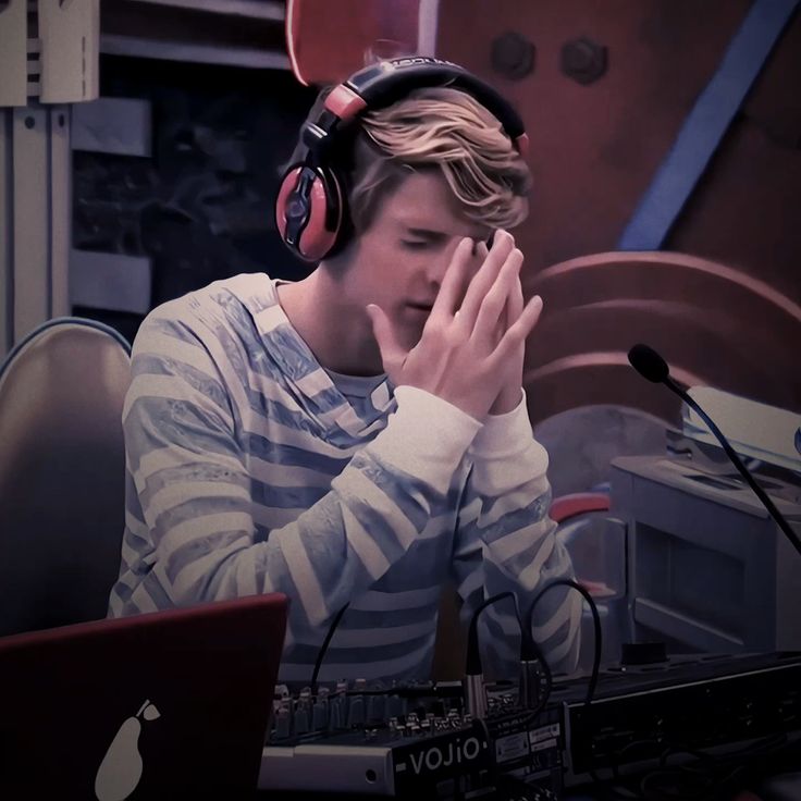 a young man wearing headphones sitting in front of a laptop computer