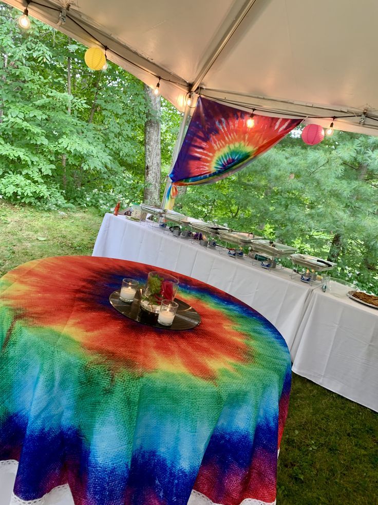 a table covered with a tie - dyed cloth under a tent