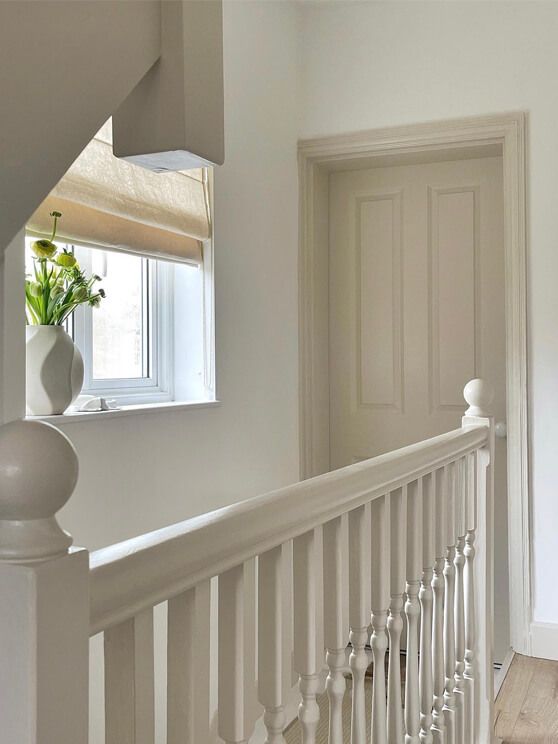 an empty room with white railings and a potted plant on the window sill