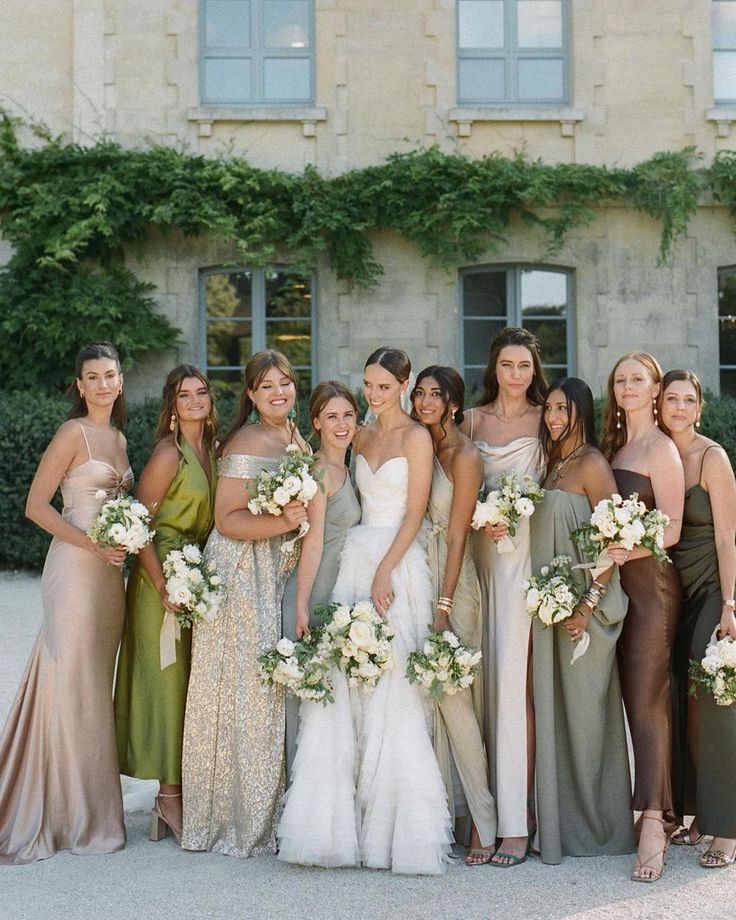 a group of women standing next to each other in front of a building holding bouquets