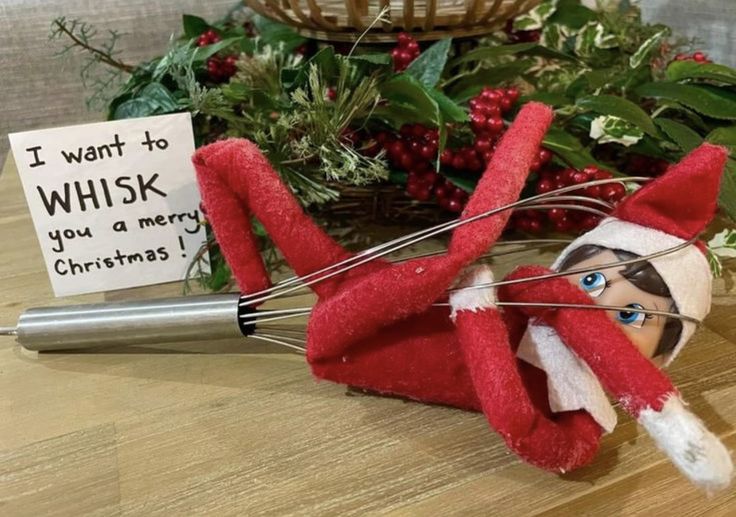 an elf is holding a whisk in front of a christmas card on the table