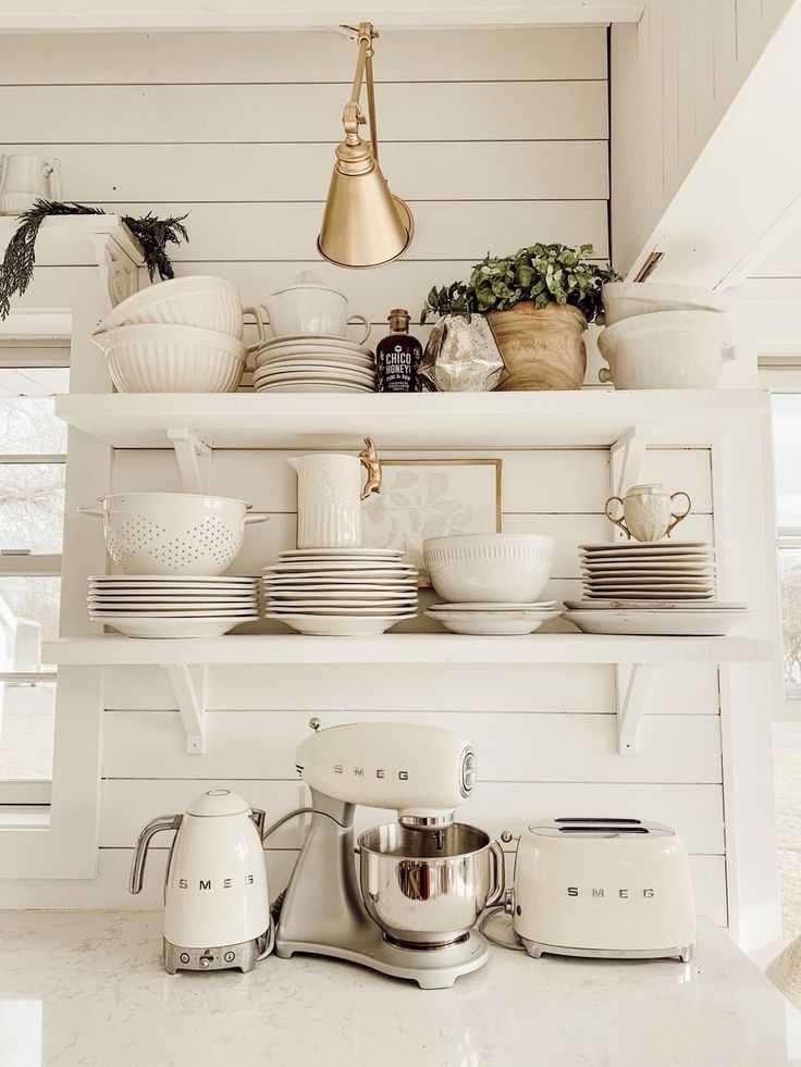 a kitchen shelf filled with white dishes and appliances