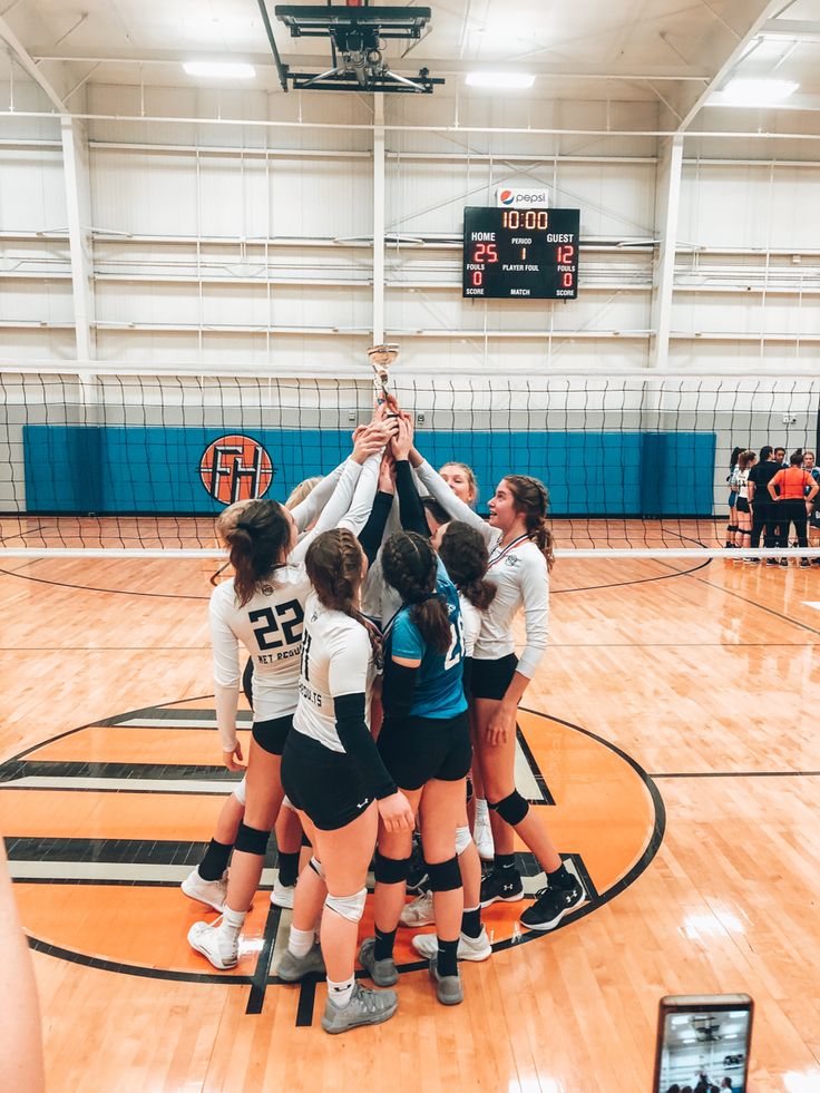 the girls volleyball team huddles together to celebrate their victory over the lady's basketball team