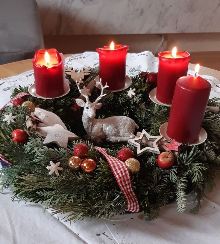 a christmas wreath with candles and ornaments on it, sitting on top of a table