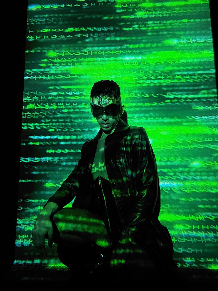 a man sitting on the ground in front of a large screen with green and black lines